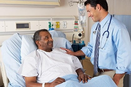 A doctor talking to a patient in a hospital bed.